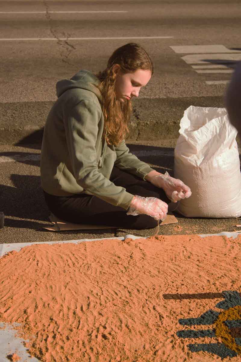 la-creatividad-en-la-metodologia Una joven crea con arena de colores una obra de arte del suelo sobre el pavimento urbano